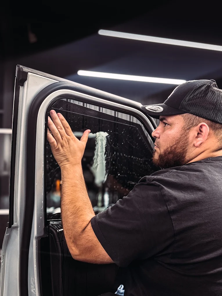 Technician applying window tint film to a car door at 86 Auto Lab